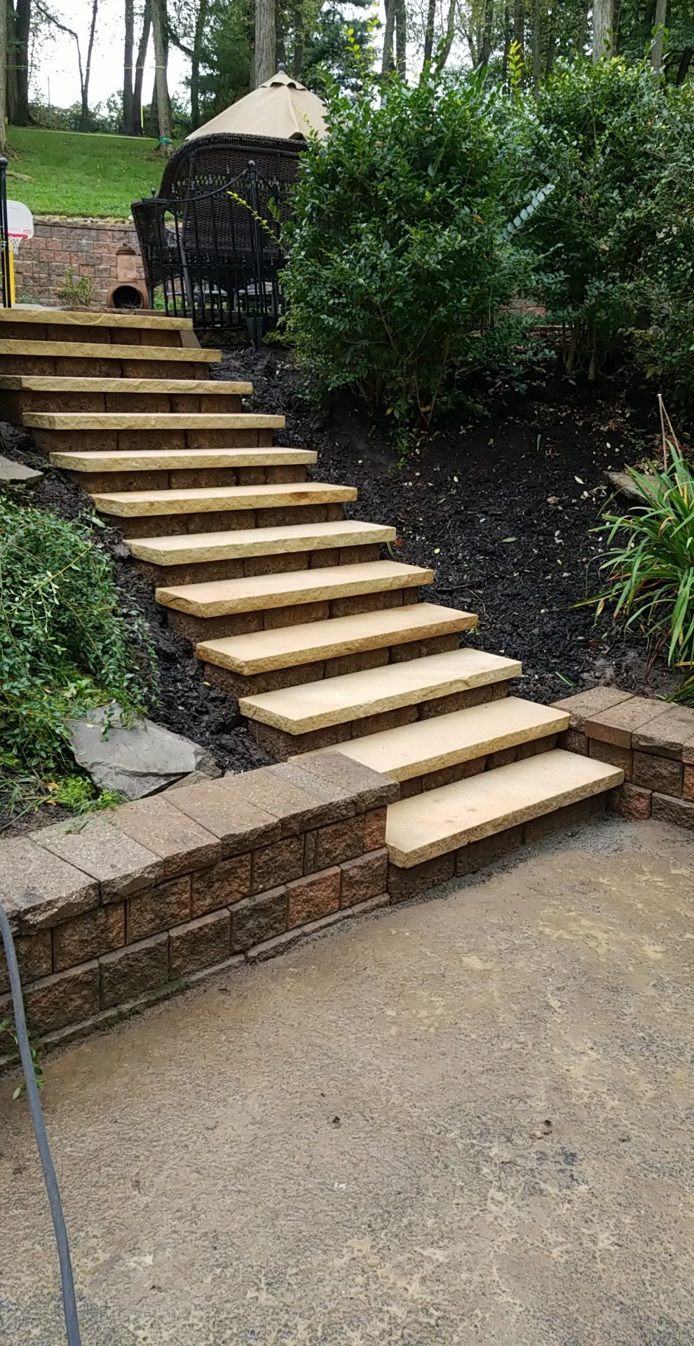 Stone slab steps on block risers climbing a mulched slope
