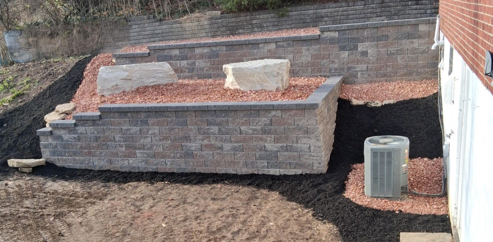 Two tiers of block retaining wall with stone boulders and red rock, built by M.S.S Landscaping